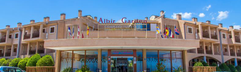 De hoofdingang van het Albir Garden Resort & Aquapark, een zandkleurig gebouw onder een strakblauwe Spaanse hemel.