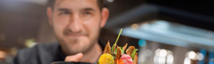 Een chef in het restaurant van het ATLANTIC Hotel Münster presenteert een culinair en kindvriendelijk gerecht.