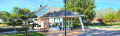 Het moderne centrale gebouw met de receptie en horeca van Vakantiepark Bad Hoophuizen, omgeven door groen.