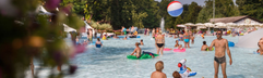 Kinderen en ouders die samen spelen met een bal in het ondiepe, kindvriendelijke zwembad van Camping Altomincio Family Park.