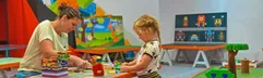 Kinderen zijn creatief aan het knutselen met grote blokken in de overdekte kidsclub van Camping de Schatberg.