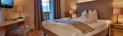 Hotelkamer met comfortabel tweepersoonsbed, nachtkastjes, moderne inrichting en zachte verlichting.