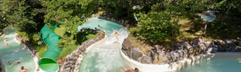 De wildwaterbaan van Aqua Mundo bij Het Meerdal die zich door een groene, bosrijke omgeving slingert, met verschillende mensen in het water.