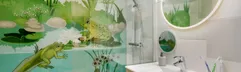 Een vrolijke badkamer in de themacottage 'Dieren in het bos' bij Erperheide, met een wandillustratie van kikkervisjes en salamanders onder water.