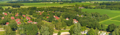 Luchtfoto van vakantiepark De Tolplas, met de grote recreatieplas in het midden, omringd door vakantiehuisjes en de groene natuur van Twente.