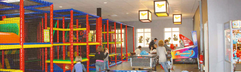 De kleurrijke indoorspeeltuin van Ferienresort Bad Bentheim met klimrekken en een airhockey tafel.