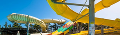 Een kluwen van gele en kleurrijke waterglijbanen die uitkomen in het zwembad van het aquapark bij Hotel Gouves Waterpark Holiday Resort.