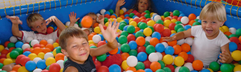 Vrolijke kinderen spelen en duiken in de kleurrijke ballenbak van de indoorspeeltuin op Eifelpark Kronenburger See.