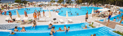 Gasten genieten van het grote, levendige zwembad met verschillende niveaus op een zonnige dag bij het kindvriendelijke Zaton Holiday Resort.