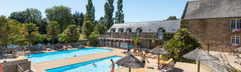 Een rustiger, omheind zwembad op camping Domaine des Ormes, omringd door ligbedden en parasols, direct gelegen bij de appartementen.
