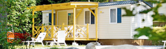 Een gezellige stacaravan met een houten veranda, gelegen tussen de rotsen en het groen op KNAUS Campingpark Lackenhäuser.