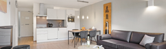 Stijlvolle en moderne woonkamer met open keuken in een appartement van Landal Ameland State, compleet met zithoek en eettafel.