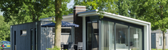 Een duurzame design bungalow met grote ramen, verscholen tussen de hoge bomen en aan het water op Landal Amerongse Berg.