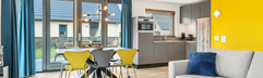 Het moderne en kleurrijke interieur van de woonkamer van een vakantievilla op Landal Berger Duinen, met een open keuken.