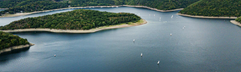 Uitzicht op het stuwmeer de Rursee, direct gelegen bij Landal Eifeler Tor, met zeilbootjes op het water in de heuvelachtige omgeving van de Eifel.
