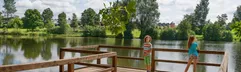 Twee kinderen staan op een houten vlonder aan de rand van het grote stuwmeer bij vakantiepark Landal Hochwald.