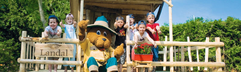 Kinderen poseren vrolijk met Bollo de Beer, de mascotte van Landal, op de veranda van de Bollo Club.