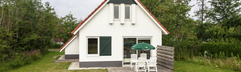 Vrijstaande witte bungalow met een terras en een grote, groene tuin op Landal Natuurdorp Suyderoogh, gelegen bij Nationaal Park Lauwersmeer.