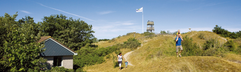 Kinderen rennen en spelen in het glooiende duinlandschap van natuurgebied de Slufter, direct naast vakantiepark Landal Sluftervallei op Texel.