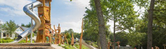 Een grote houten avonturenspeeltuin met diverse klimtoestellen en een glijbaan, gelegen in het groen op Landal Sonnenberg.