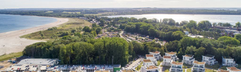 Luchtfoto van vakantiepark Landal Travemünde, met de vakantiehuizen gelegen aan de jachthaven en de Oostzeekust.