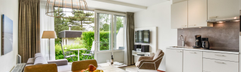 Het moderne interieur van een appartement op Landal Vitamaris, met een open keuken en een ruime houten eettafel die uitkijkt op het terras.
