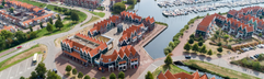 Een luchtfoto van het uitgestrekte Marinapark Volendam, dat laat zien hoe de vakantiehuizen en de jachthaven direct aan het Markermeer liggen.