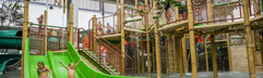 en jongetje roetsjt van een brede, groene glijbaan in de grote waterspeeltuin van Aqua Mundo in Center Parcs Park Allgäu.