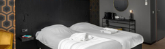 Stijlvolle en moderne hotelkamer in Roompot Klein Vink met een comfortabel tweepersoonsbed en donkere, sfeervolle inrichting.
