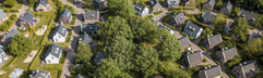 Luchtfoto van de luxe vakantiehuizen van Dormio Resort Maastricht, omgeven door bomen en groene velden.
