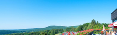 Prachtig uitzicht vanaf een balkon met rode bloemen over het heuvellandschap van de Rhön in Beieren bij Rhön Park Aktiv Resort.