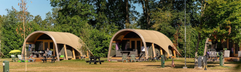 Twee luxe en uniek vormgegeven lodges op een groot grasveld, omringd door bomen op Vakantiecentrum 't Schuttenbelt.