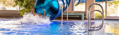 De grote, blauwe tunnelglijbaan in het overdekte zwembad van Vakantiepark Aquadelta zorgt voor een spetterend einde in het water.