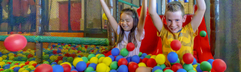 Lachende kinderen spelen in de ballenbak vol gekleurde ballen