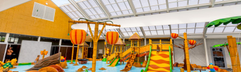 Het overdekte waterspraypark op Vakantiepark Eiland van Maurik vol met kleurrijke speeltoestellen, glijbanen en waterkanonnen.