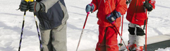 Kinderen in rode skipakken krijgen skiles op een besneeuwde piste en leren de basis van het skiën in de Harz.