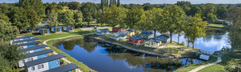Luchtfoto van luxe lodges direct gelegen aan de vijver op de camping