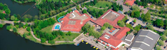 Luchtfoto van Vakantiepark Weerterbergen, met het centrale faciliteitengebouw aan het water, omgeven door groene natuur.
