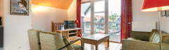 Het gezellige interieur van de woonkamer in een waterwoning, met een comfortabele zithoek en uitzicht op het water en de steigers.