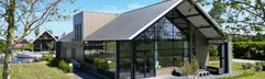 Het moderne, architectonische hoofdgebouw van Waterpark Zwartkruis met grote glazen pui, gelegen aan het water.