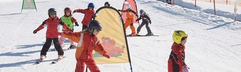 Jonge kinderen krijgen skiles in het kinderland op de piste in de Harz, met poortjes en een skileraar.