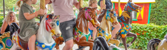 Gezin geniet van een ritje op de vrolijk gekleurde draaimolen met paarden in Wunderland Kalkar.
