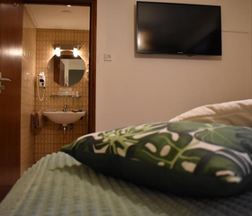 Hotelkamer in Hotel Atlanta met een groen bed en een open deur naar de en suite badkamer