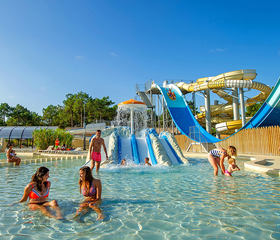 Kinderen en volwassenen spelen in het grote zwembad van het waterpark met diverse spectaculaire glijbanen op de kindvriendelijke camping Atlantic Club Montalivet.