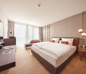 Een ruime en luxe hotelkamer in het ATLANTIC Hotel Münster, met een comfortabel groot bed voor het hele gezin.