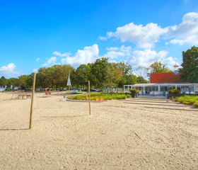 Het ruime zandstrand van Bad Hoophuizen met een beachvolleybalnet, direct gelegen aan het Veluwemeer.