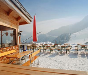 Een zonnig, besneeuwd terras van een berghut met uitzicht op de skipistes en bergen van het Zwarte Woud.