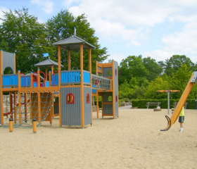 Het grote, houten klimkasteel in de ruime zandspeeltuin op Bospark De Schaapskooi, klaar voor avontuurlijke kinderen.
