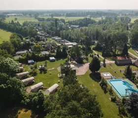 Luchtfoto van het groene en ruim opgezette Bospark Markelo, met een duidelijk zicht op het zwembad, de vakantiehuisjes en de omliggende natuur.