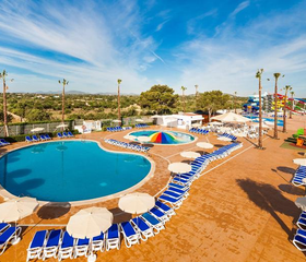 Rond zwembad met blauw-witte parasols en zonneterras bij Bouganvilla Hotel Appartementen Sa Coma Mallorca